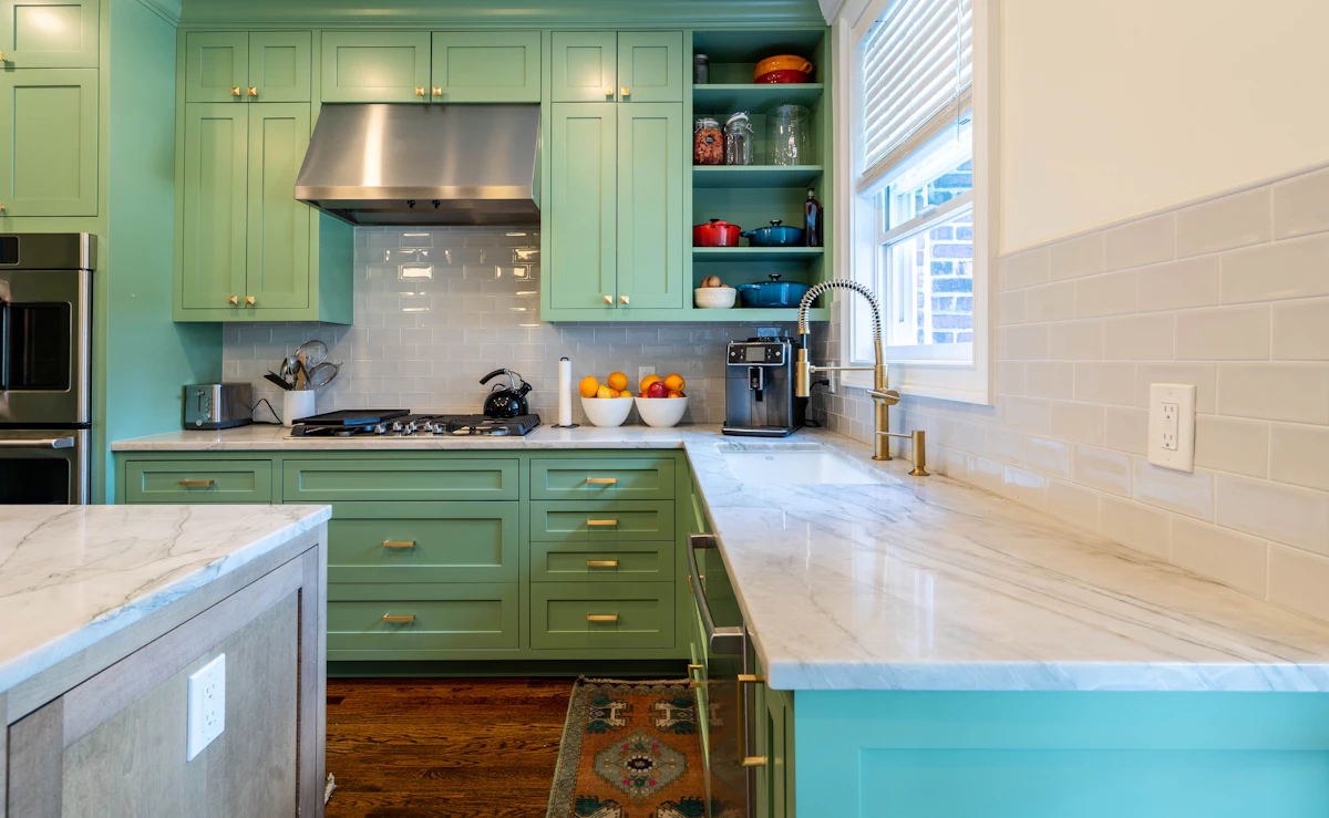 Painted sage green kitchen cabinets with marble countertop