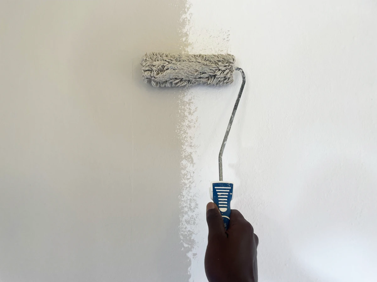 Painter using a roller to apply fresh white paint to an interior wall